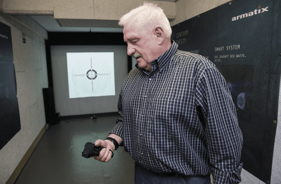Gun designer Ernst Mauch looks at the Armatix iP1 while violating one of the four safety rules. (courtesy washingtonpost.com)