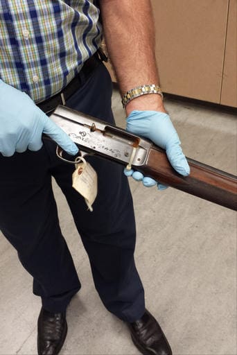In this June 2015 photo released by the Seattle Police on Thursday, March 17, 2016, Detective Michael Ciesynski holds the shotgun which rock legend Kurt Cobain used to kill himself on April 8, 1994. Police did not say why they took the photos last year or why they're releasing them to the public at this time. (Seattle Police via AP)